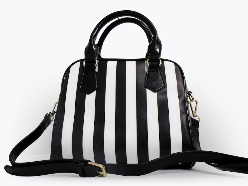 May include: A black and white striped satchel handbag with a black shoulder strap and gold hardware.