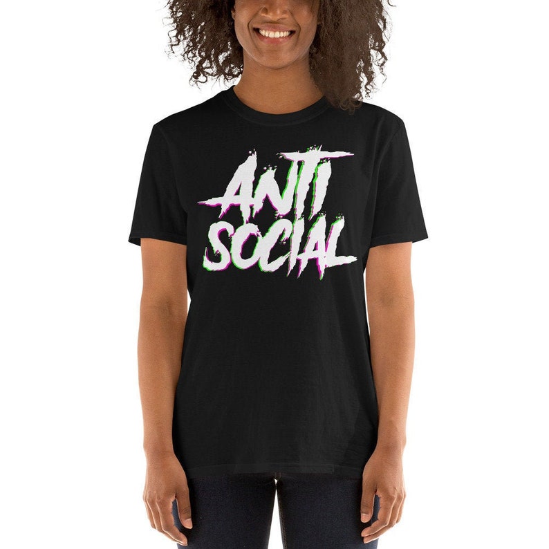 Puede incluir: Camiseta negra de manga corta con un gr&aacute;fico blanco que dice "ANTI SOCIAL" en una fuente con efecto glitch con acentos verdes y morados.