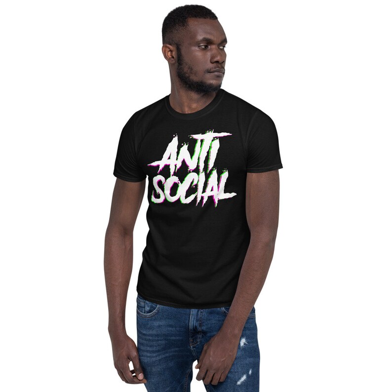 Puede incluir: Una camiseta negra con un gr&aacute;fico blanco que dice "ANTI SOCIAL" en una fuente con efecto glitch con acentos rosas y verdes.
