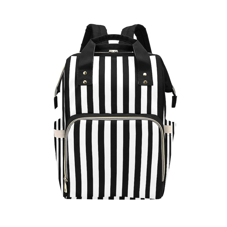 May include: Black and white striped backpack with multiple compartments and pockets. The bag has a top handle and adjustable shoulder straps. The exterior features a bold vertical stripe pattern, with gold-colored zippers and accents.