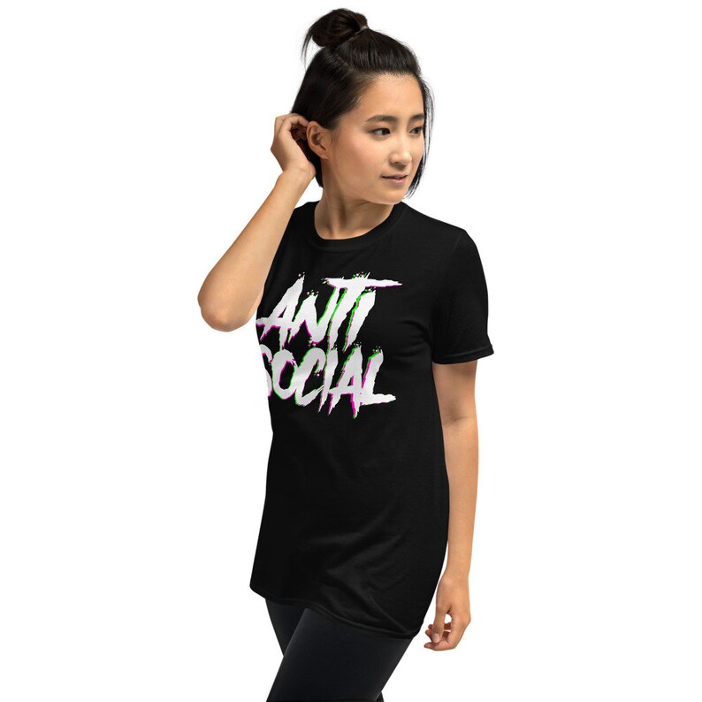 Puede incluir: Camiseta negra con un gr&aacute;fico blanco que dice "ANTI SOCIAL" en una fuente distorsionada y con errores con acentos rosas y verdes.