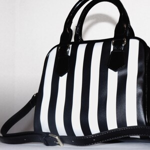 May include: Black and white striped handbag with a black leather handle and shoulder strap.
