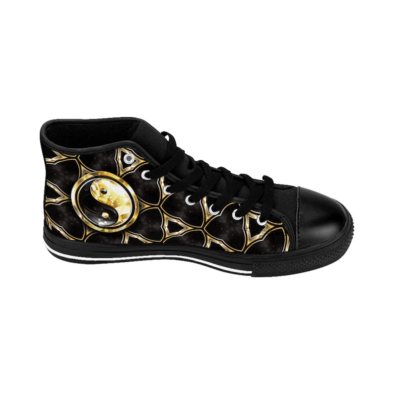 May include: Black high-top canvas sneaker featuring a gold and black yin yang design. The shoe has a black toe cap, laces, and sole. The design includes a gold yin yang symbol and a gold geometric pattern.