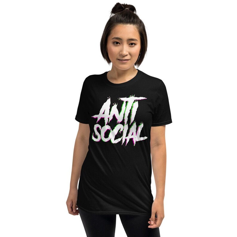 Puede incluir: Camiseta negra de manga corta con un gr&aacute;fico blanco que dice "ANTI SOCIAL" en una fuente estilizada con acentos verdes y morados.