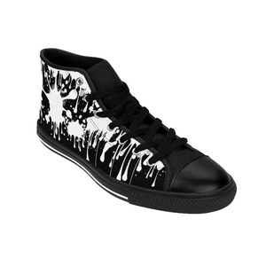 May include: Black high-top canvas sneakers with a white paint splatter design. The shoes have black laces and a white stripe around the sole.