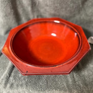 Peut inclure: Un bol en céramique rouge brillant avec un bord octogonal. Le bol a un intérieur profond et une surface lisse et réfléchissante. Le bord extérieur a un bord légèrement surélevé. Ce bol décoratif convient au service ou à l'exposition.