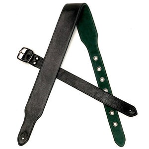 May include: Black leather guitar strap with a green suede backing. The strap features a silver buckle and eyelets for adjustment. The guitar strap is designed for comfort and durability.