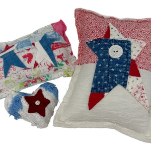 May include: Three handmade fabric pillows with a patriotic theme. The pillows are made from patchwork fabric in red, white, and blue with stars and a button detail.