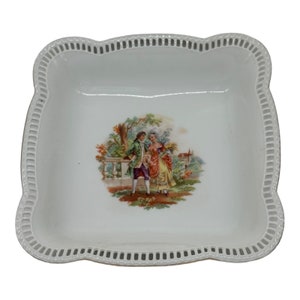 Puede incluir: Un plato de porcelana blanca con un borde festoneado y un delicado diseño floral con una pareja en un jardín.