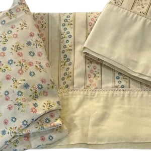 May include: A set of bedding featuring a floral pattern with pink and blue flowers on a cream background. The fitted sheet has a cream and white striped pattern with a floral border. The pillowcase is cream with a floral border.