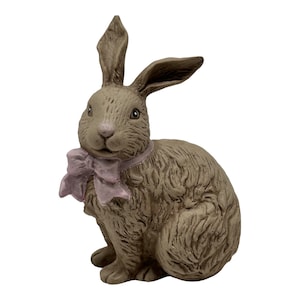 Könnte beinhalten: Eine braune Keramik-Hasenfigur mit einer rosa Schleife um den Hals. Der Hase sitzt mit aufgestellten Ohren und geschlossenen Augen.