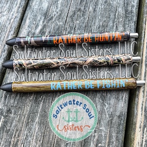 May include: Three camouflage-patterned pens with black ink. The pens have the text "Rather Be Huntin'" and "Rather Be Fishin'" printed on them. The pens are made by Saltwater Soul Sisters, LLC.