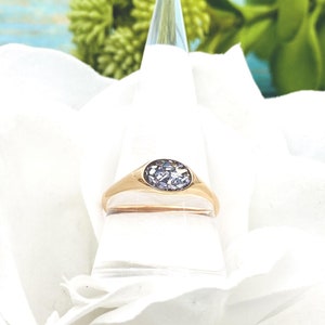 May include: A gold signet ring with a purple gemstone set in the centre.