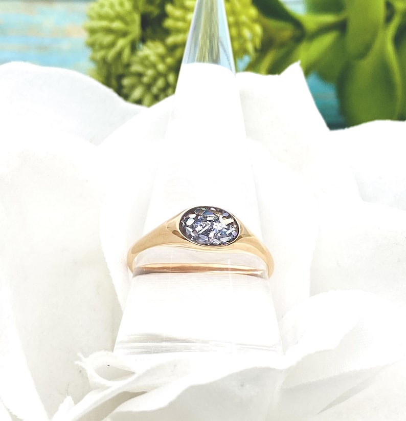 May include: A gold signet ring with a purple gemstone set in the centre.
