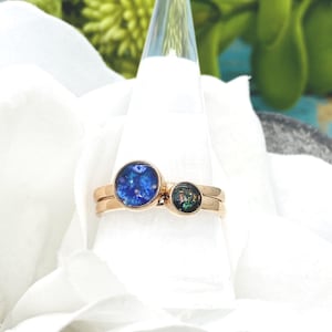May include: Two gold rings with blue and green opal stones. The rings are stacked on top of each other.