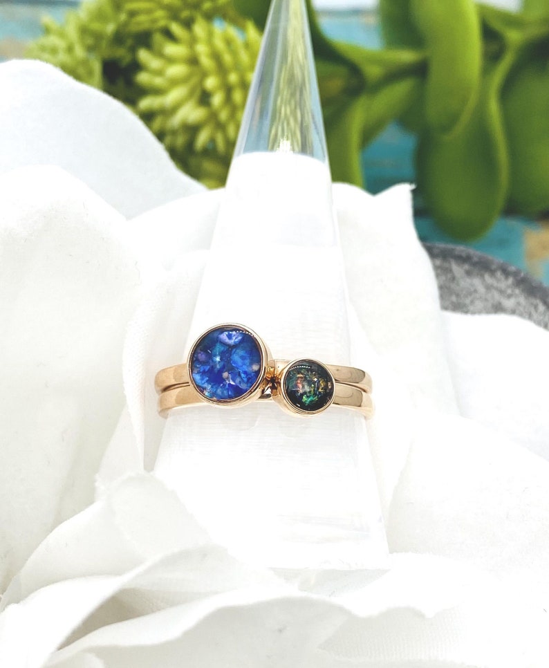 May include: Two gold rings with blue and green opal stones. The rings are stacked on top of each other.