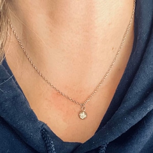 May include: A delicate gold chain necklace with a small round pendant.