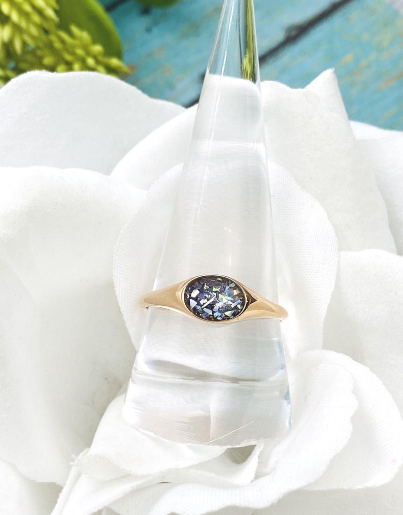 May include: A gold ring with a round iridescent stone set in a bezel setting.
