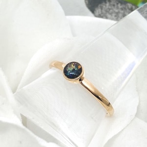 May include: A gold ring with a round, iridescent opal gemstone set in the center.