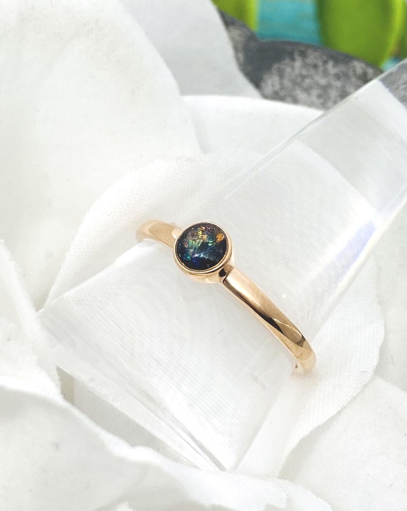 May include: A gold ring with a round, iridescent opal gemstone set in the center.