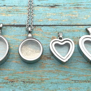 May include: Four silver locket pendants, two round and two heart-shaped, with clear glass inserts. The round lockets are on chains, while the heart lockets are on a single loop.
