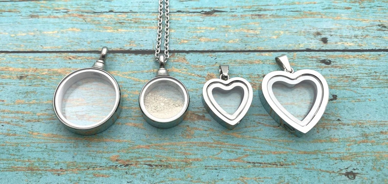 May include: Four silver locket pendants, two round and two heart-shaped, with clear glass inserts. The round lockets are on chains, while the heart lockets are on a single loop.