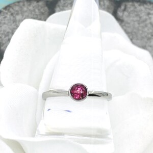 May include: A silver ring with a pink oval gemstone set in the center.