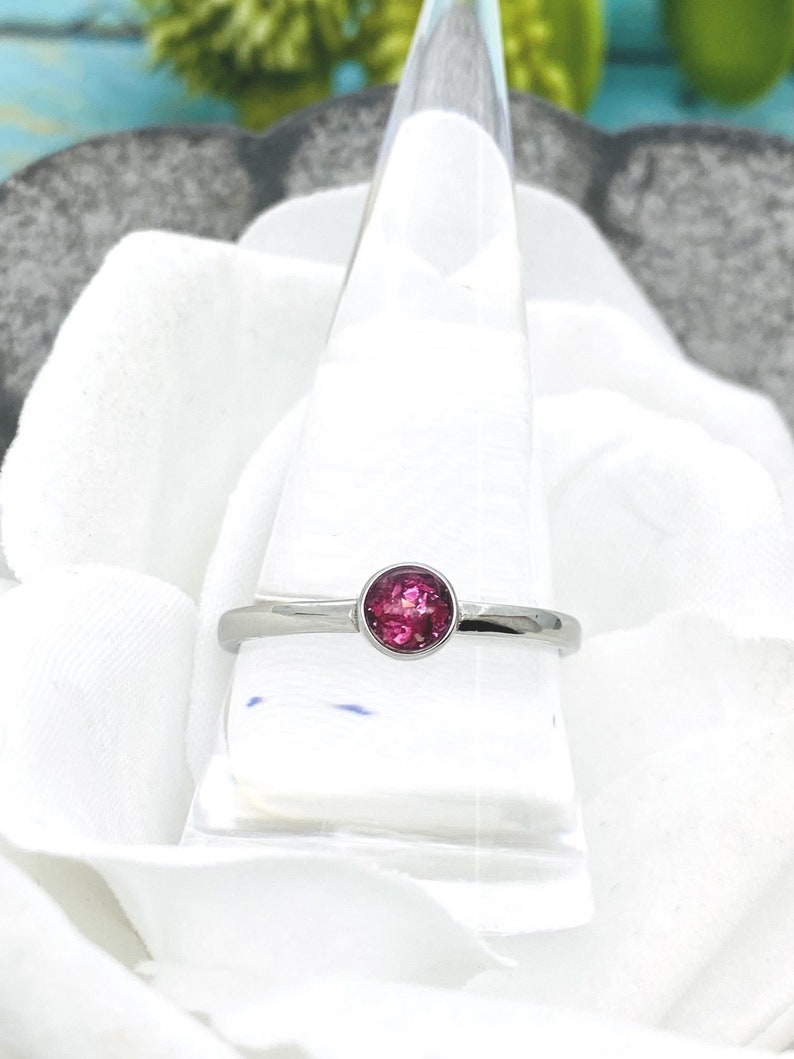 May include: A silver ring with a pink oval gemstone set in the center.