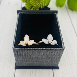 K&ouml;nnte beinhalten: Zwei Ringe mit einem f&uuml;nfbl&auml;ttrigen Blumendesign. Die Ringe sind aus Silber und Ros&eacute;gold und haben wei&szlig;en Glitzer, der in die Bl&uuml;tenbl&auml;tter eingebettet ist.