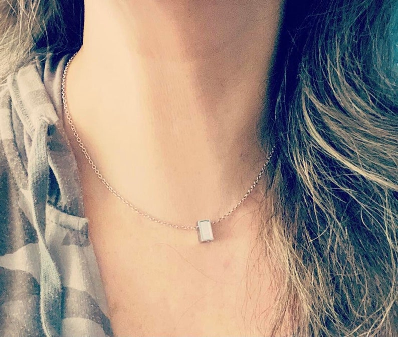 May include: A silver chain necklace with a small, rectangular pendant.