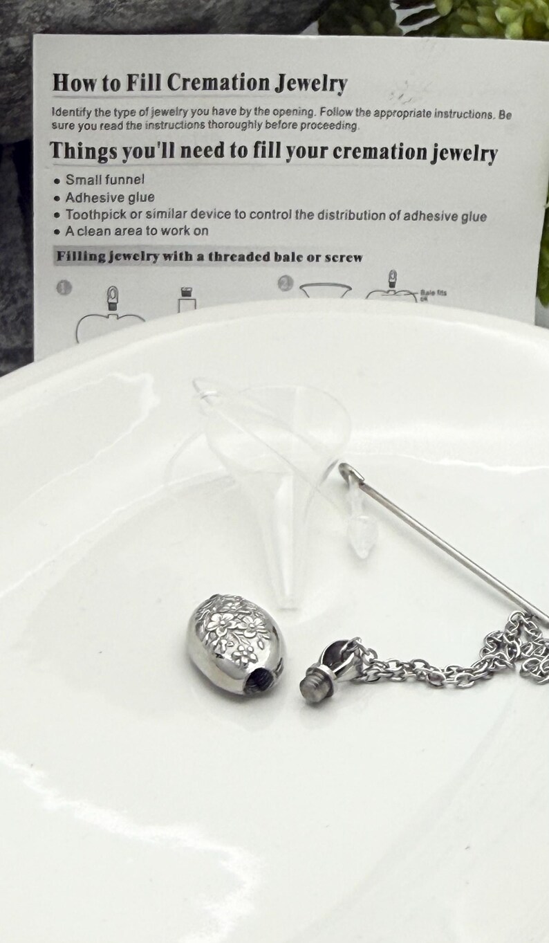 May include: A silver cremation jewelry pendant with a floral design, a small funnel, and a chain. The image includes instructions on how to fill the jewelry, including a list of necessary items.