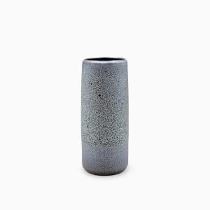 Może przedstawiać: Cylindryczny wazon ceramiczny o nakrapianym, teksturowanym wykończeniu w odcieniach szarości i czerni. Powierzchnia posiada gęsty, cętkowany wzór, który zmienia odcień od góry do dołu, zakończony gładkim, otwartym, okrągłym otworem wlotowym.