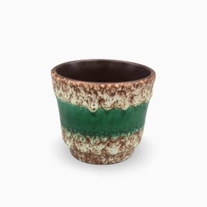 Può includere: Un vaso in ceramica con interno marrone scuro ed esterno testurizzato caratterizzato da un'ampia fascia verde smeraldo lucida al centro, in contrasto con motivi di smalto maculato color crema e marrone sulle sezioni superiore e inferiore.