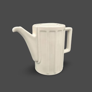 Può includere: Teiera in ceramica color crema con un lungo beccuccio e un manico. La teiera presenta scanalature verticali lungo il corpo e un coperchio piatto. Il design è minimalista e moderno, adatta per servire il tè.