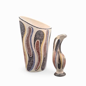 May include: A tall, slanted ceramic vase and a smaller, slender ceramic pitcher, both featuring a textured, off-white base with vertical, wavy abstract patterns in shades of dark grey, brown, and yellow, with a speckled, matte finish.