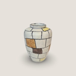 May include: A ceramic vase with a cream-colored base, featuring a patchwork design of brown, yellow, and tan squares outlined in black. The vase has a rounded body and a narrow neck, suitable for home decor.