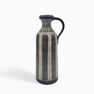 Puede incluir: Una jarra de cerámica alta con borde, asa y base de color azul oscuro. El cuerpo presenta una superficie gris claro decorada con rayas verticales gris oscuro y filas alternas de pequeños puntos blancos en forma de gota.