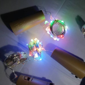 May include: A set of four battery-operated copper wire fairy lights with multi-colored LED bulbs. The lights are coiled and wrapped around small brown battery packs.