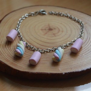 May include: A silver chain bracelet with pink and multi-coloured marshmallow charms.