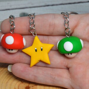 Può includere: Tre portachiavi con personaggi della serie di videogiochi Super Mario Bros. I portachiavi sono realizzati in pasta polimerica e presentano un fungo rosso e bianco, un fungo verde e bianco e una stella gialla.