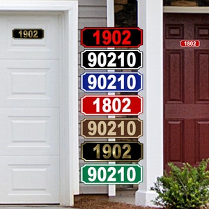 May include: A close-up of a white post with six different house number signs attached. The signs are in various colors, including black, red, blue, brown, gold, and green. The numbers on the signs are 1902 and 90210.