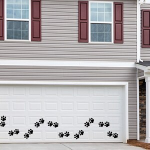 May include: A white garage door with a black number "1140" on the left side. A row of black paw prints are on the bottom of the door.