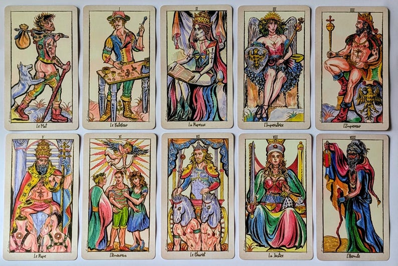 May include: A set of ten tarot cards arranged in two rows, featuring colorful, hand-drawn illustrations of figures like The Fool, The Magician, The High Priestess, The Empress, The Emperor, The Hierophant, The Lovers, The Chariot, Justice, and The Hermit.
