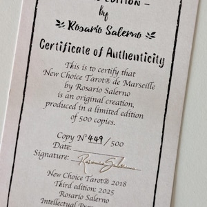 May include: A rectangular certificate of authenticity for the New Choice Tarot de Marseille Third Edition by Rosario Salerno. The document features black text on a light background, stating it is a limited edition of 500 copies, copy number 449.
