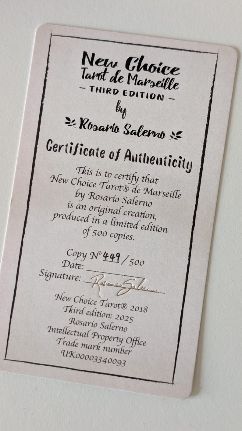 May include: A rectangular certificate of authenticity for the New Choice Tarot de Marseille Third Edition by Rosario Salerno. The document features black text on a light background, stating it is a limited edition of 500 copies, copy number 449.