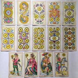 May include: A collection of fourteen tarot cards featuring intricate illustrations of coins, floral patterns, and figures. The cards display various arrangements of yellow circular coins, ornate botanical designs, and four human figures in colorful attire.