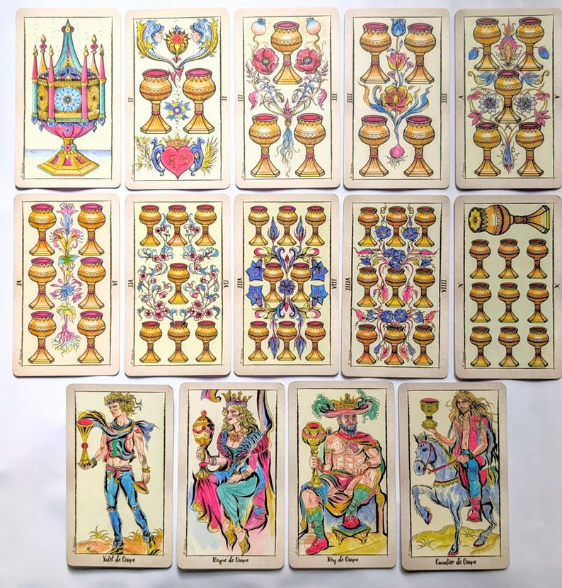 May include: A collection of fourteen tarot cards from the suit of cups, arranged in three rows. The cards feature illustrations of golden chalices, floral motifs, and four human figures, including a page, queen, king, and knight on horseback.