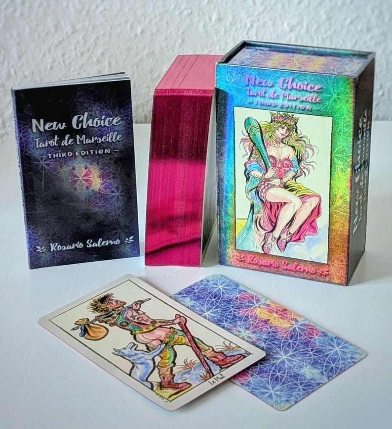 May include: A New Choice Tarot de Marseille Third Edition deck by Rosario Salerno featuring a box with a holographic finish, a guidebook, and a stack of cards with metallic pink edges. Two tarot cards are displayed, one showing Le Mat.
