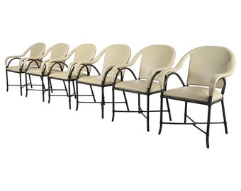 May include: Set of six off-white leather dining chairs with black metal frames. The chairs have curved backs and arms.