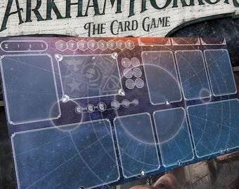 May include: A rectangular Arkham Horror The Card Game playmat featuring a dark blue cosmic space background with white grid lines, card placement slots, and circular resource icons. The top banner displays the game title in bold black lettering.
